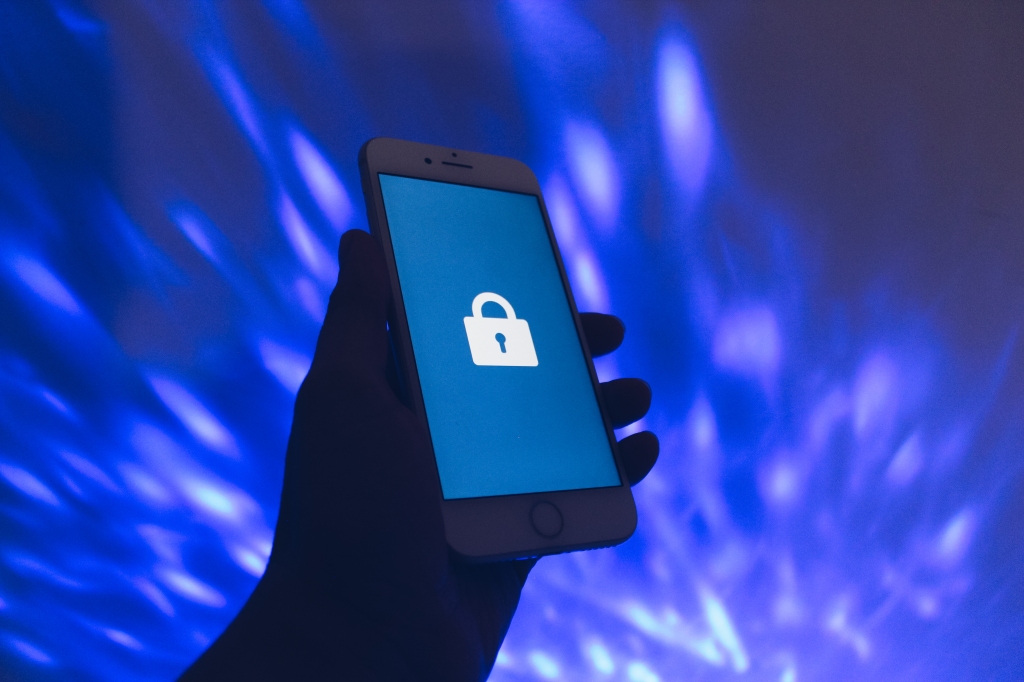 A hand, holding their phone with a lock on the screen and taking back their privacy one encrypted message at a time.